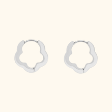 Load image into Gallery viewer, Silver-colored flower-shaped hoop earrings on a light yellow background