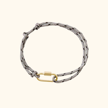 Load image into Gallery viewer, Grey bracelet with a gold clasp on a light yellow background