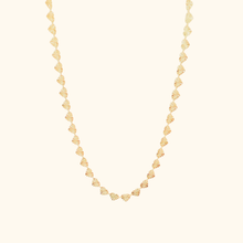 Load image into Gallery viewer, Gold heart chain necklace on a light yellow background.