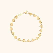 Load image into Gallery viewer, Gold bracelet with heart designs on a light yellow background.