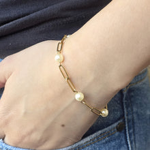Load image into Gallery viewer, Gold bracelet with pearls on a wrist against a denim jeans
