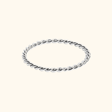 Load image into Gallery viewer, Silver-colored twisted ring on a light yellow background.
