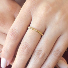 Load image into Gallery viewer, Gold ring on a finger with a soft focus background
