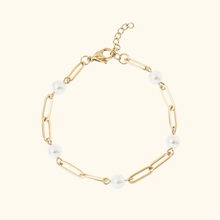 Load image into Gallery viewer, Gold-colored bracelet with pearls on a light yellow background
