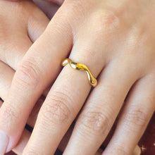 Load image into Gallery viewer, Gold wavy ring on a finger with a blurred background
