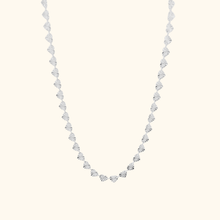 Load image into Gallery viewer, Silver heart chain necklace on a light yellow background.

